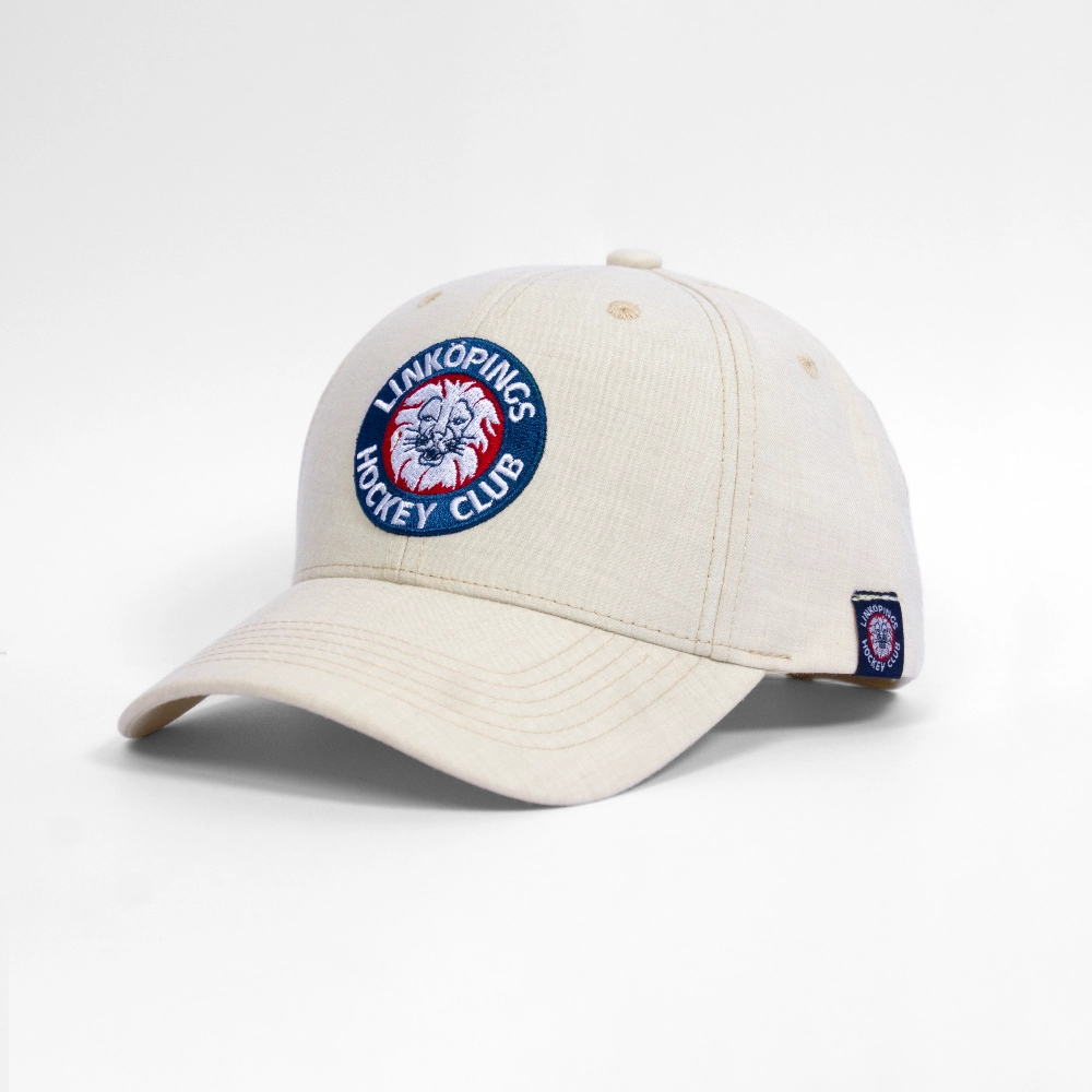 En gräddfärgad baseballkeps med Linköpings Hockey Clubs (LHC) broderade cirkulära logotyp framtill, med ett lejonhuvud i rött, vitt och blått.